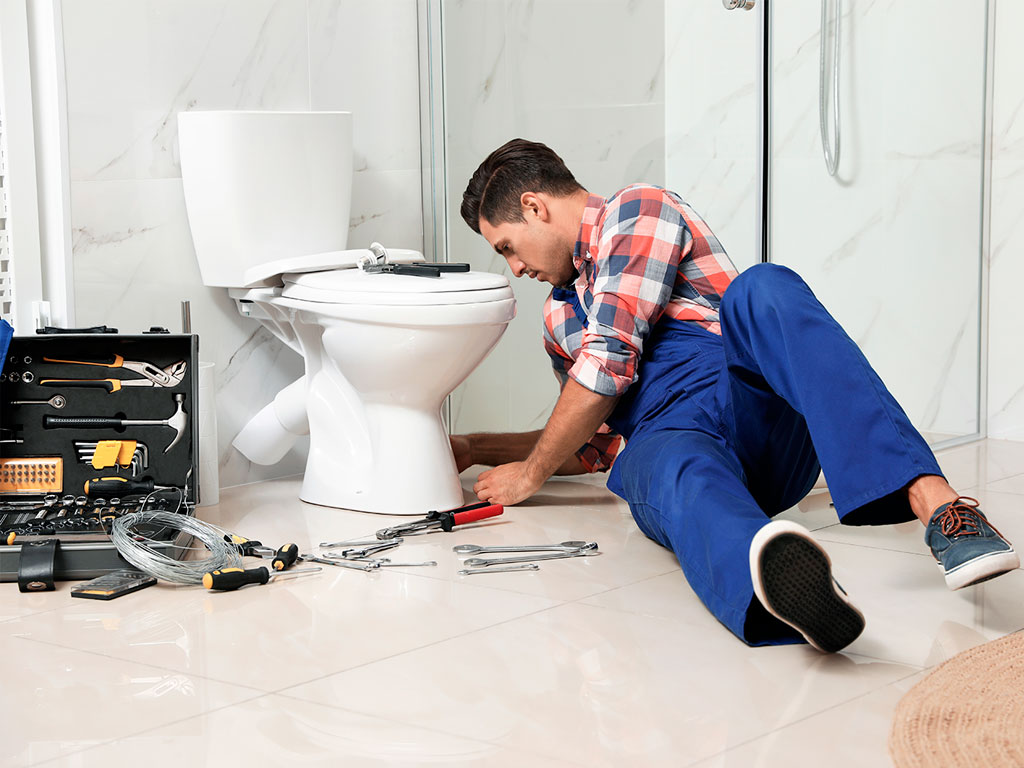man with a toolbox working on a broken toilet
