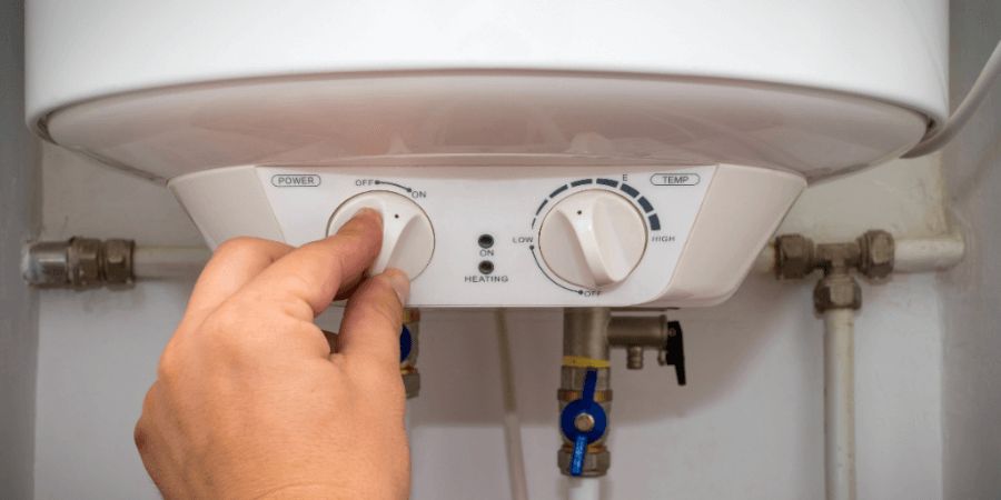 person adjusting the dial settings on a water heater