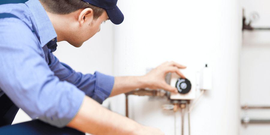 technician adjusting water heater thermostat